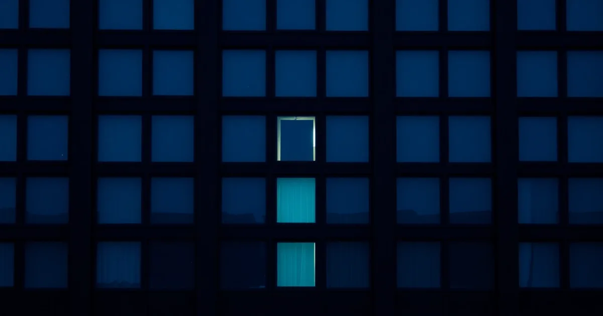 A dark facade of identical windows, a few lit from within, illustrating amended return: fixing a US filing abroad