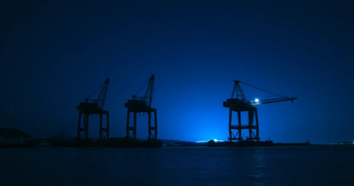 Harbour gantry cranes silhouetted against the night sky, illustrating Capital losses across US and UK