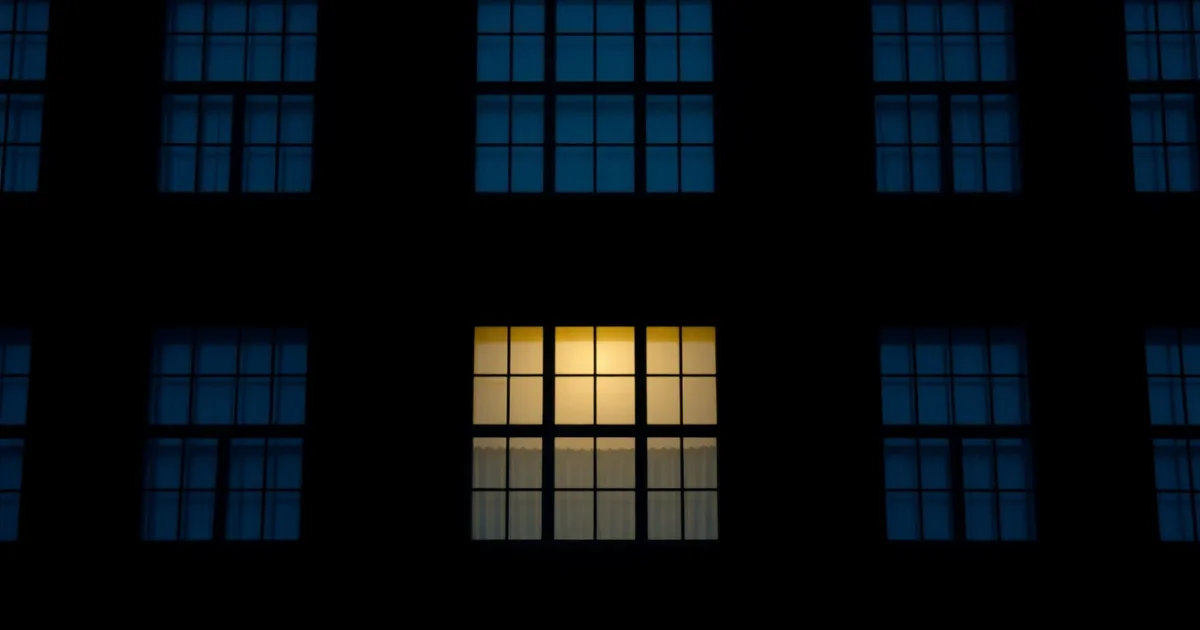 A dark facade of identical windows, a few lit from within, illustrating Filing a US return from the UK