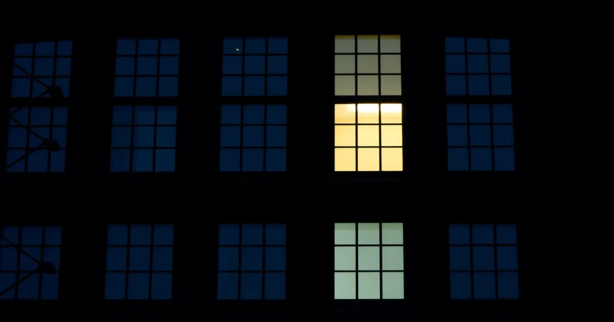 A dark facade of identical windows, a few lit from within, illustrating Foreign currency mortgage gains and US tax