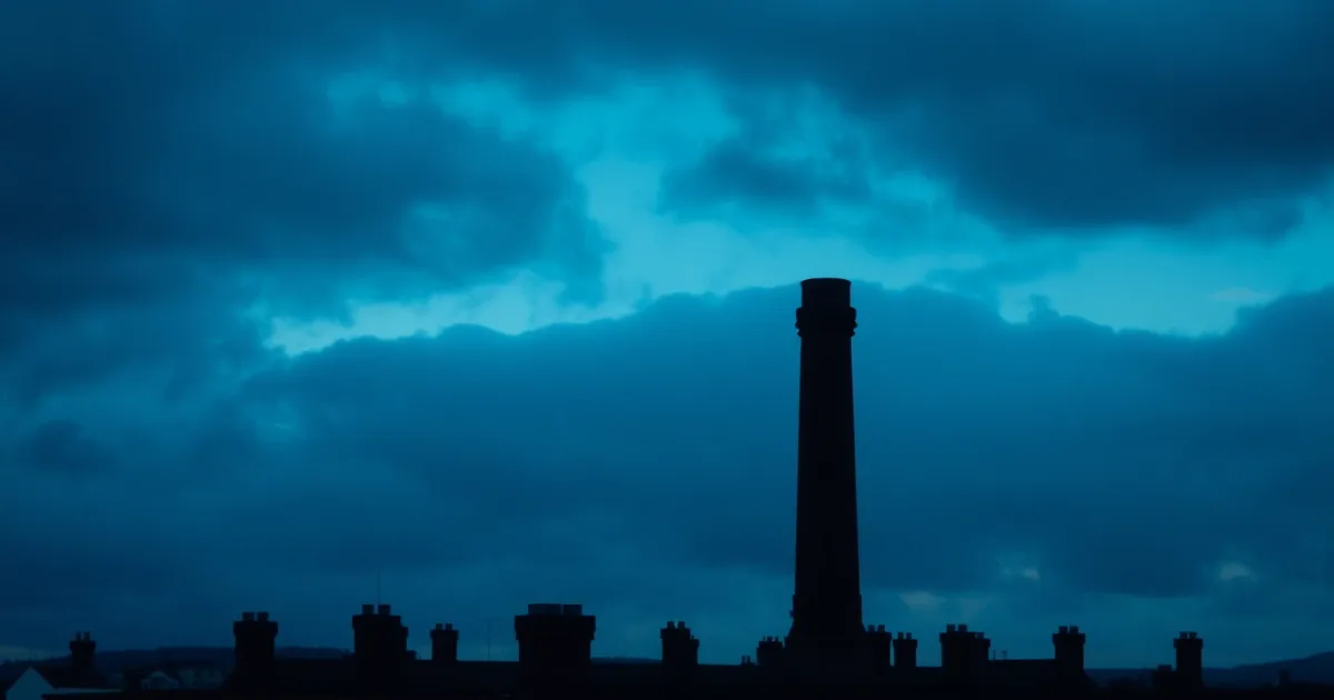 A red brick chimney skyline under heavy cloud, illustrating going freelance in the UK as an American