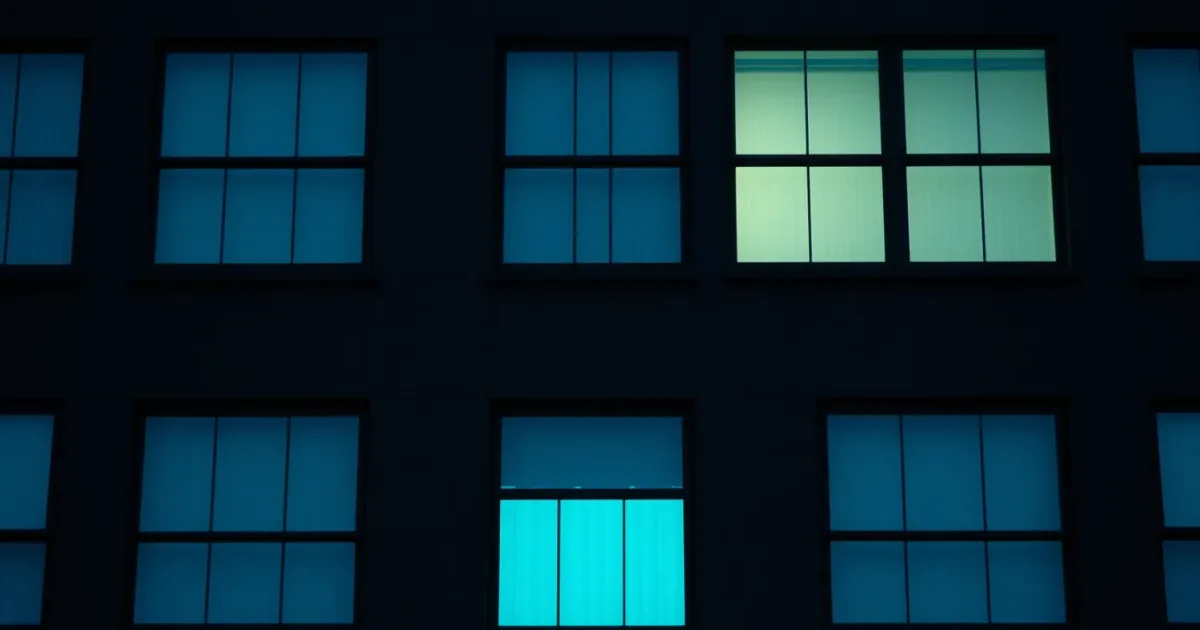 A dark facade of identical windows, a few lit from within, illustrating military pay and US tax while abroad