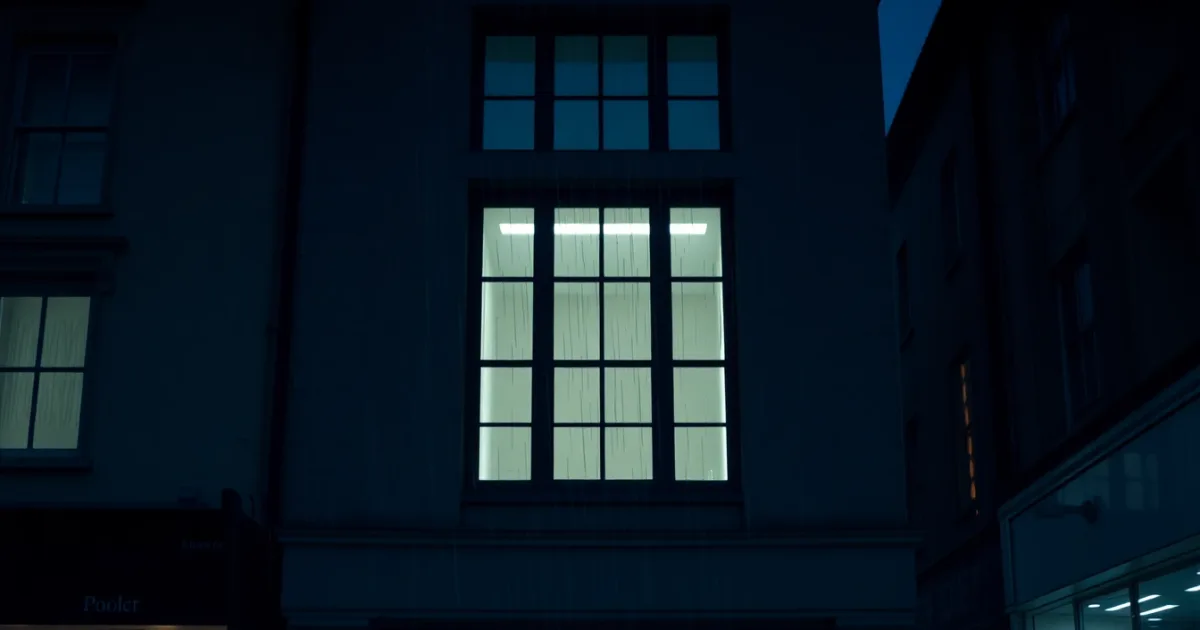 A rain-streaked window above a British high street at night, illustrating Register for Self Assessment by 5 October