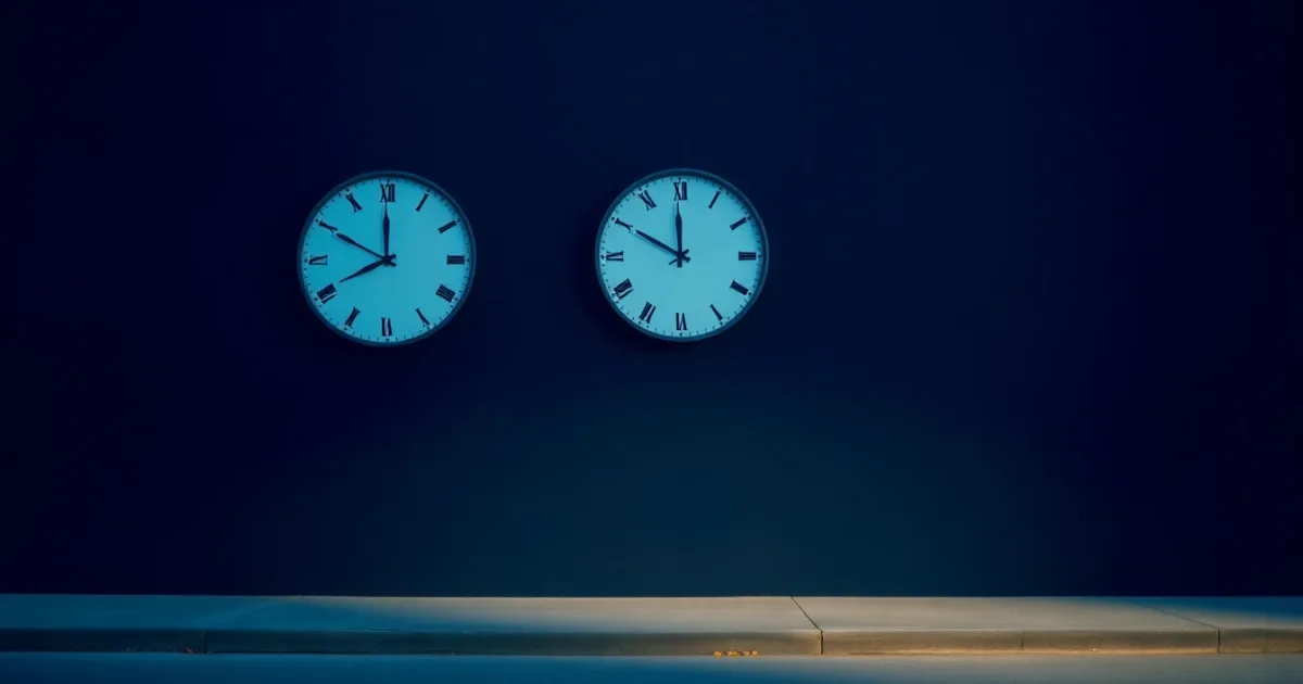 Two clocks on a dark wall showing different hours, illustrating schedule C and UK sole trader accounts