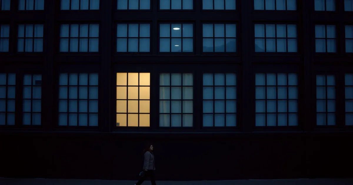 A dark facade of identical windows, a few lit from within, illustrating Self-employment tax for US expats