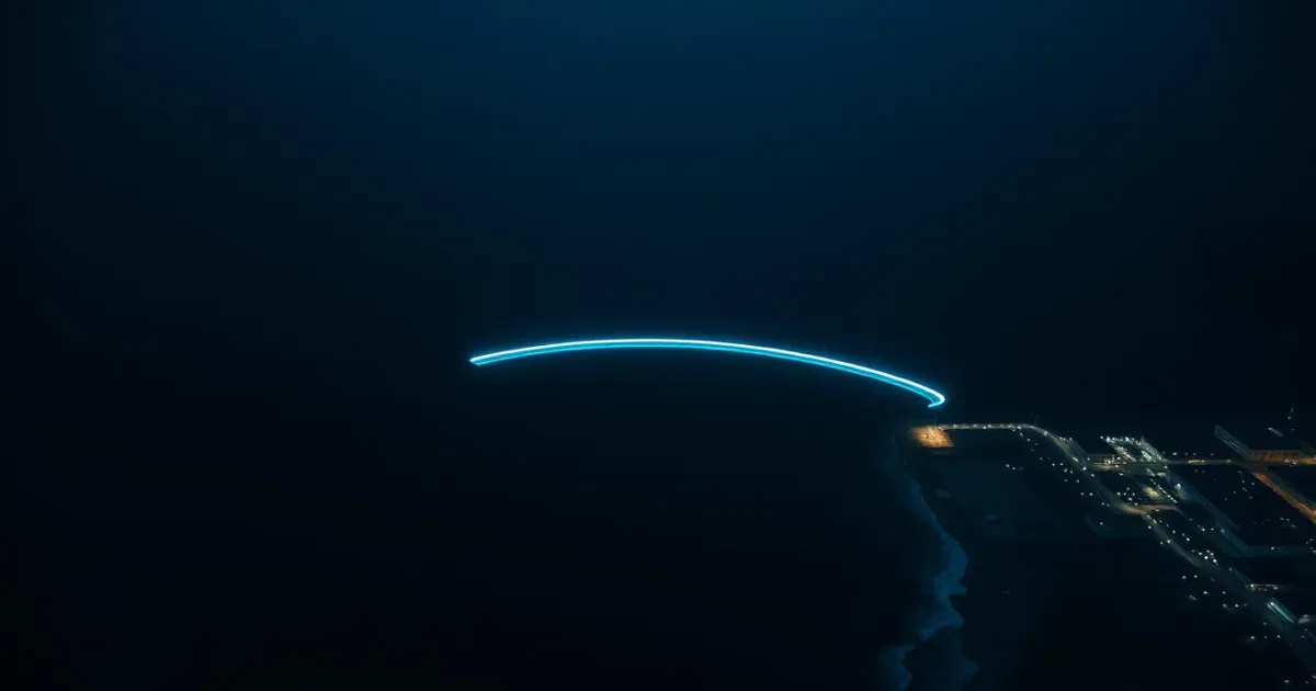 An arc of light across a night ocean between two coastlines, illustrating transferring money between the US and UK