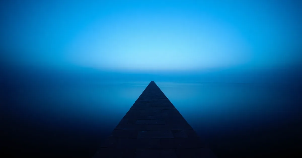 A stone causeway running out across still water at dusk, illustrating US LLC profits and UK tax