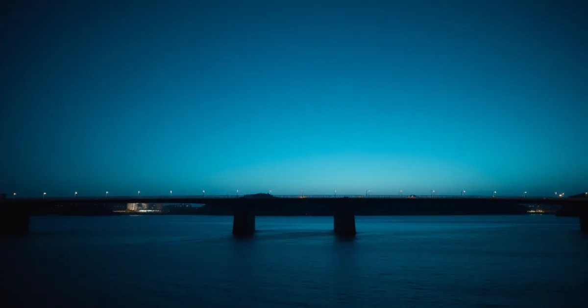 A suspension bridge photographed from the riverbank at dawn, illustrating Dividend withholding rate: the US-UK treaty